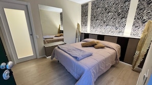 A bedroom with a bed, a mirror, and a wall with a floral pattern. - Lucca in Villa San Donato (Lucca)