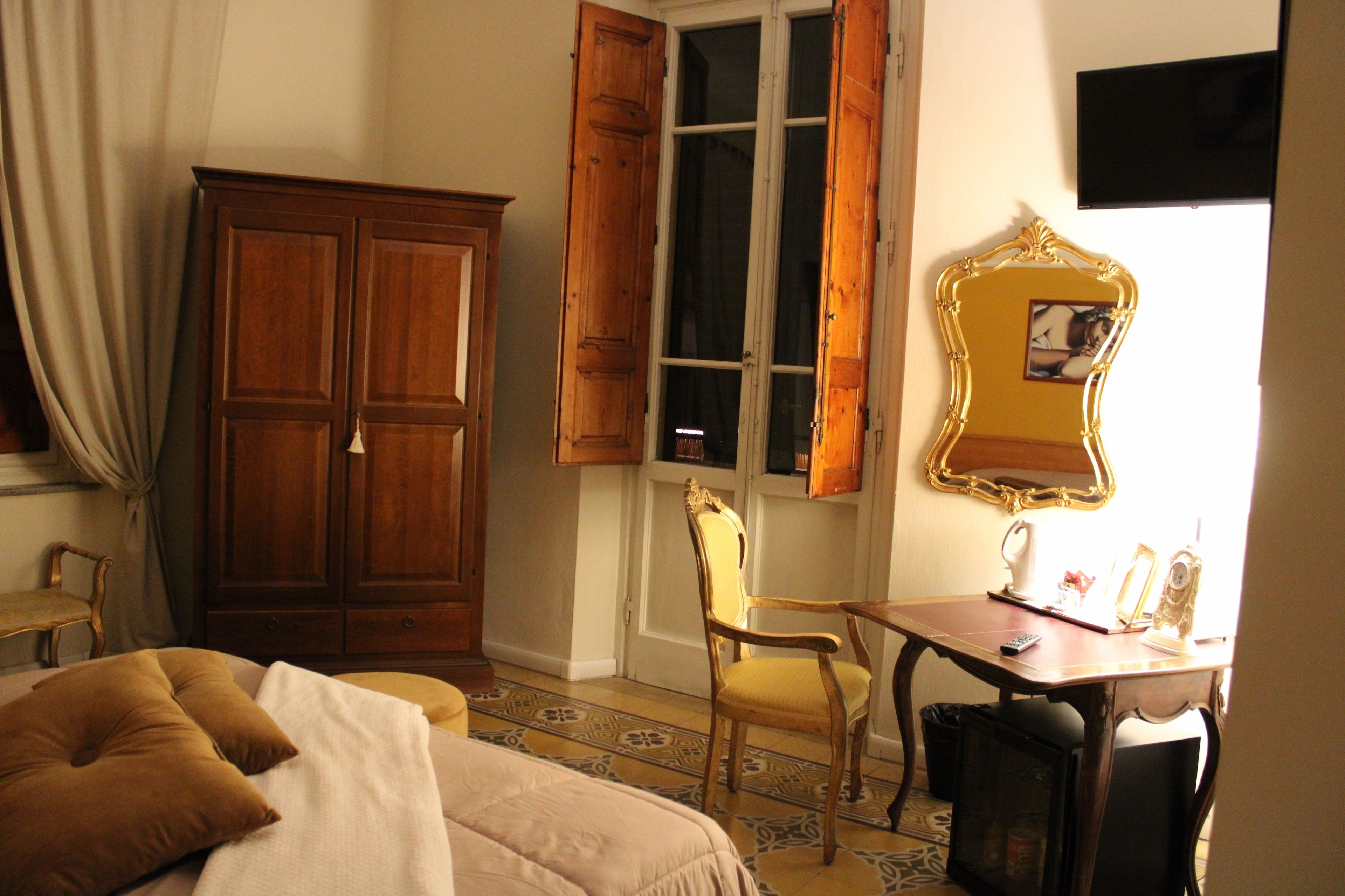 Ein Schlafzimmer mit einem Bett, einem Holzschrank, einem Schreibtisch mit Stuhl und einem Spiegel.