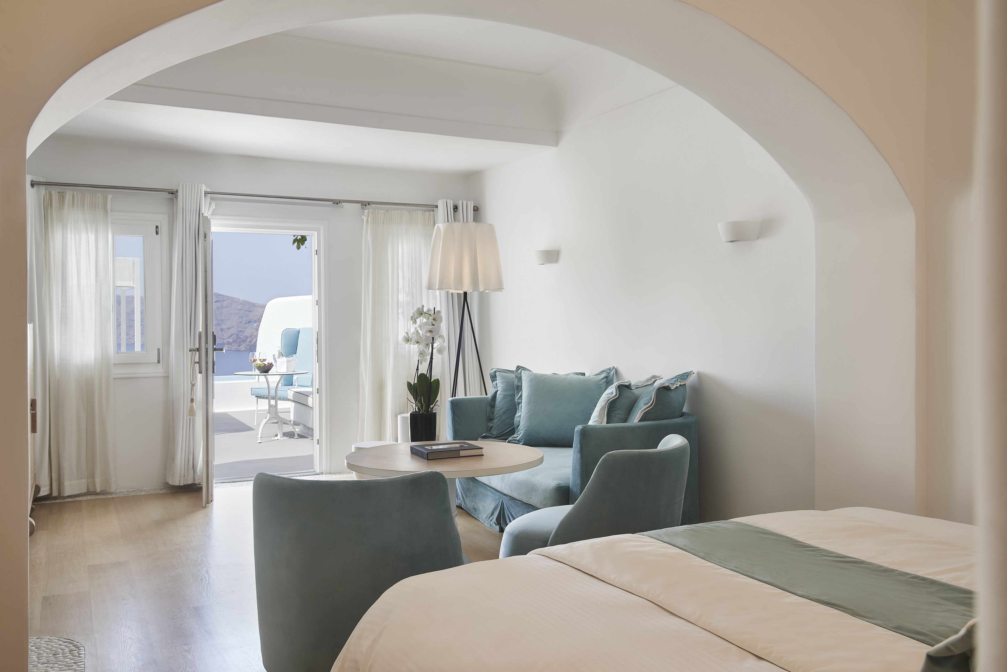 Habitación de hotel moderna con cama, sofá, una mesita y vistas al exterior.