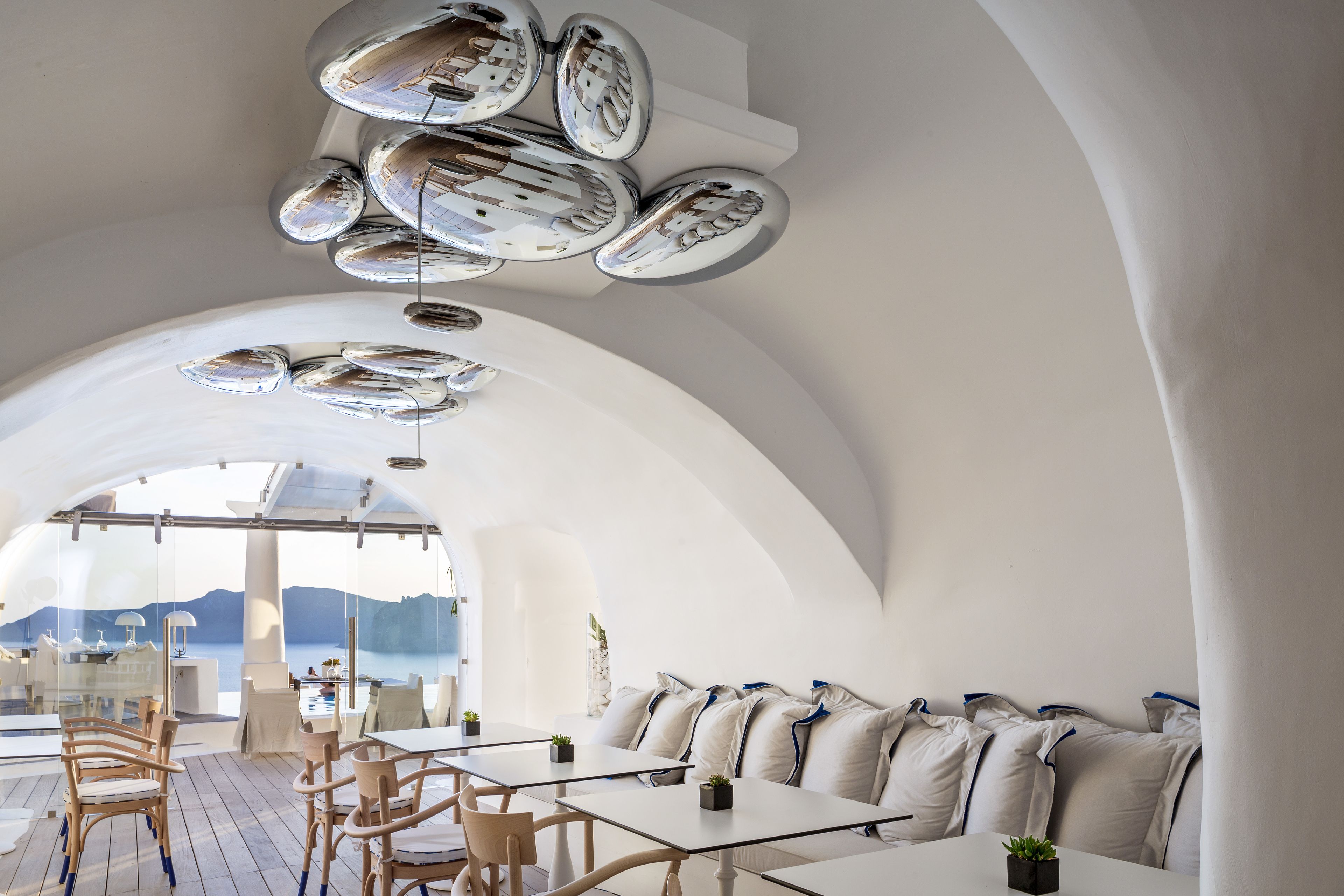 A modern interior with a dining area, seating, and a view of the sea.