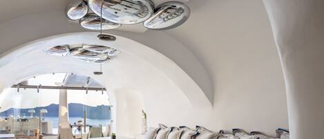 A modern interior with a dining area, seating, and a view of the sea.