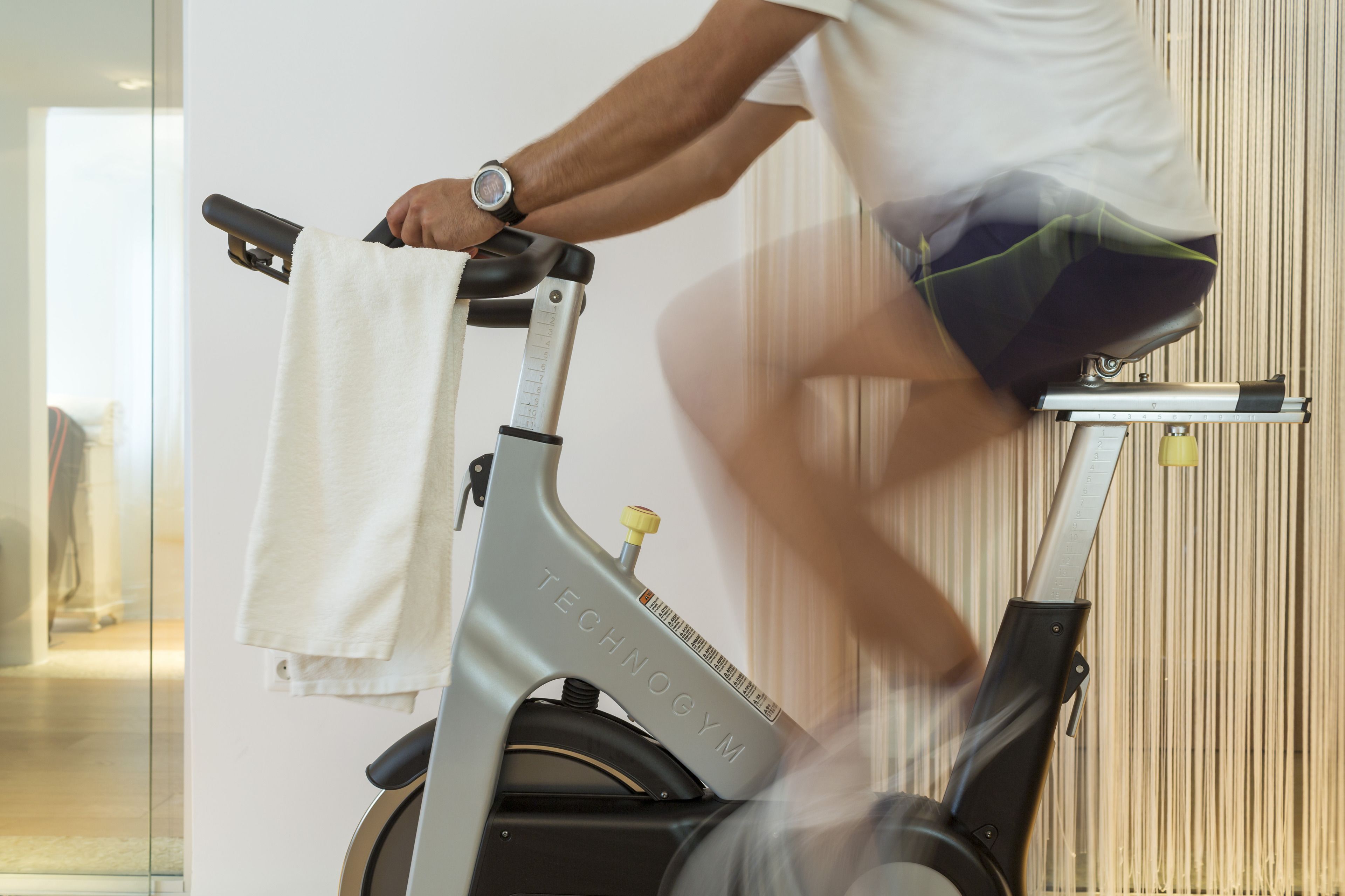 Eine Person fährt ein Ergometer, ein Handtuch hängt am Lenker.
