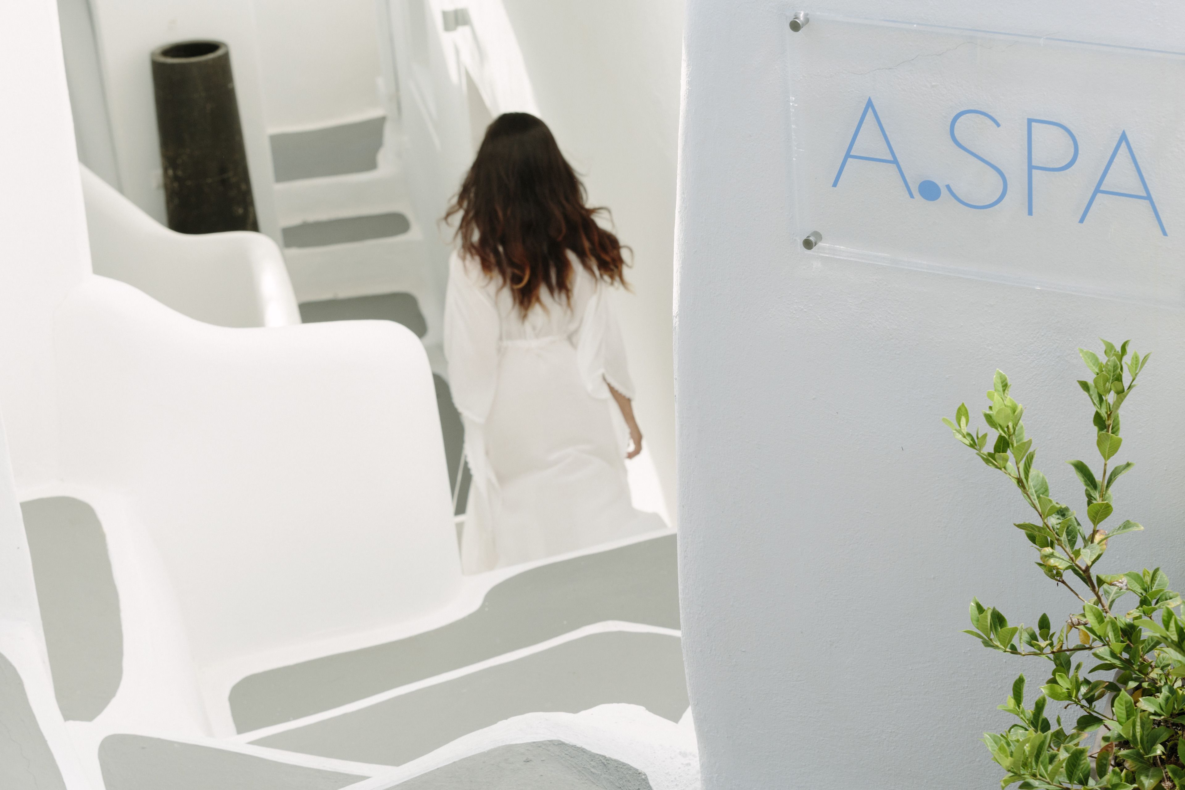 A person walking up a white staircase in a modern building with a sign reading "A.SPA".