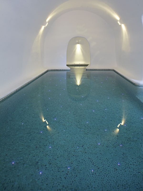 Relax by the serene indoor pool, featuring a rectangular pool and a central, illuminated structure.