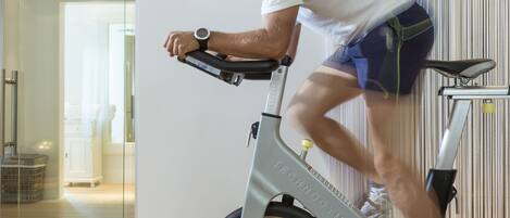 A person riding an exercise bike indoors with a visible brand name on the bike.