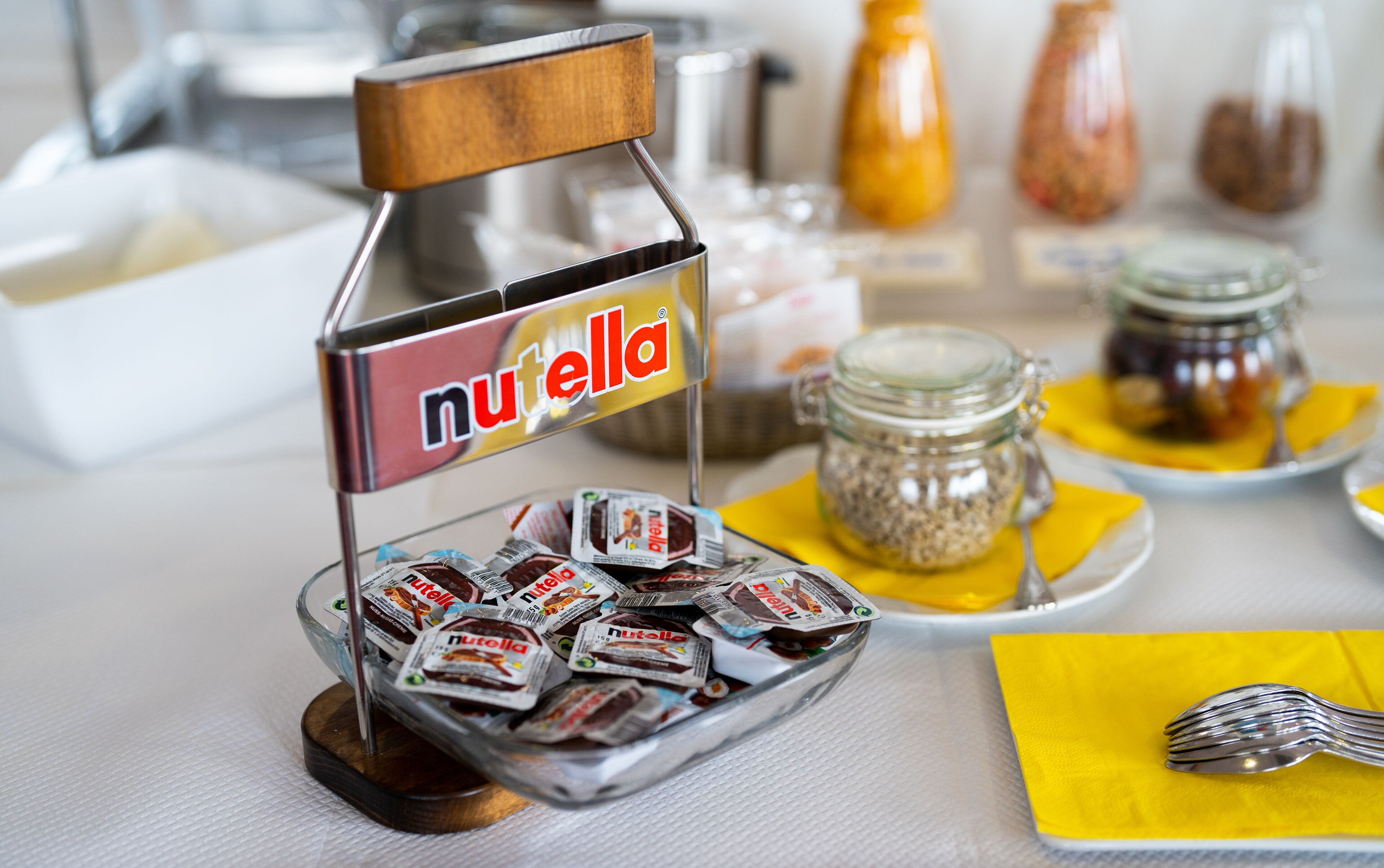 A buffet table with a Nutella dispenser and various food items.