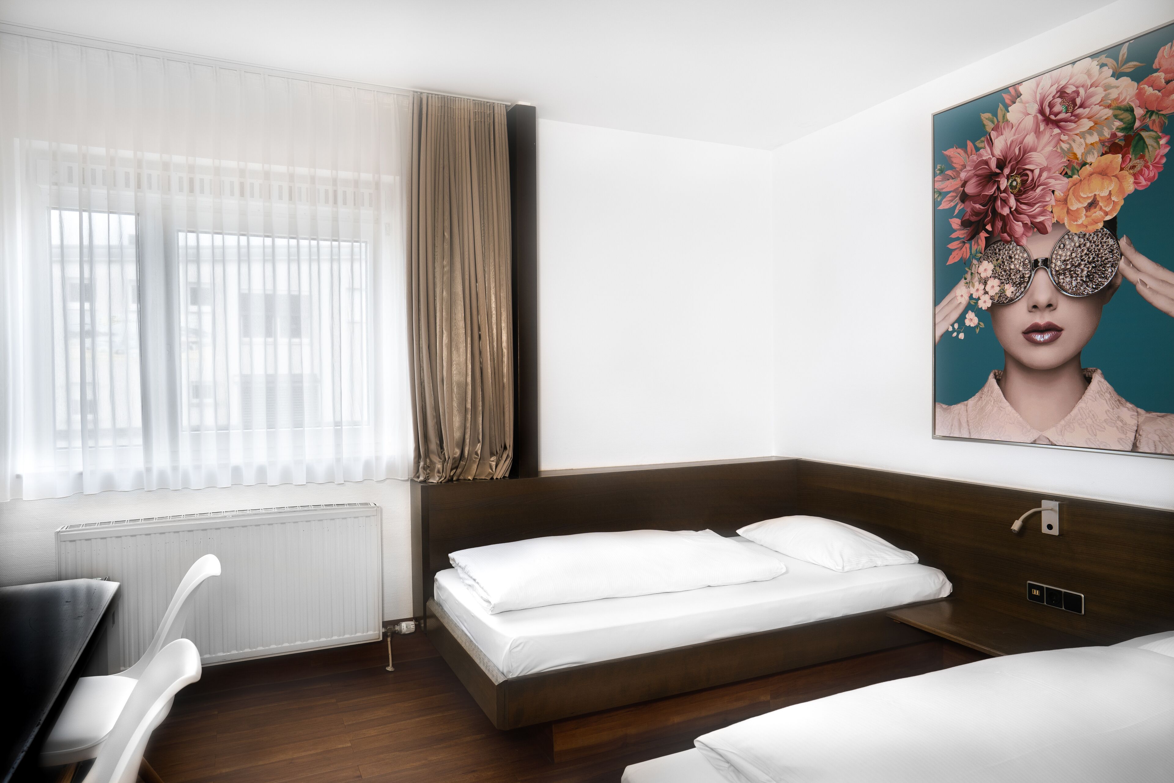 Ein modernes Hotelzimmer mit einem Bett, einem Schreibtisch und einem großen Fenster mit Vorhängen.