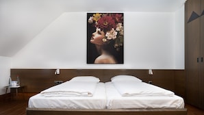 A modern bedroom with a large bed, a nightstand, and a wall-mounted painting. - eXo Individual Hotel Heilbronn (Heilbronn)