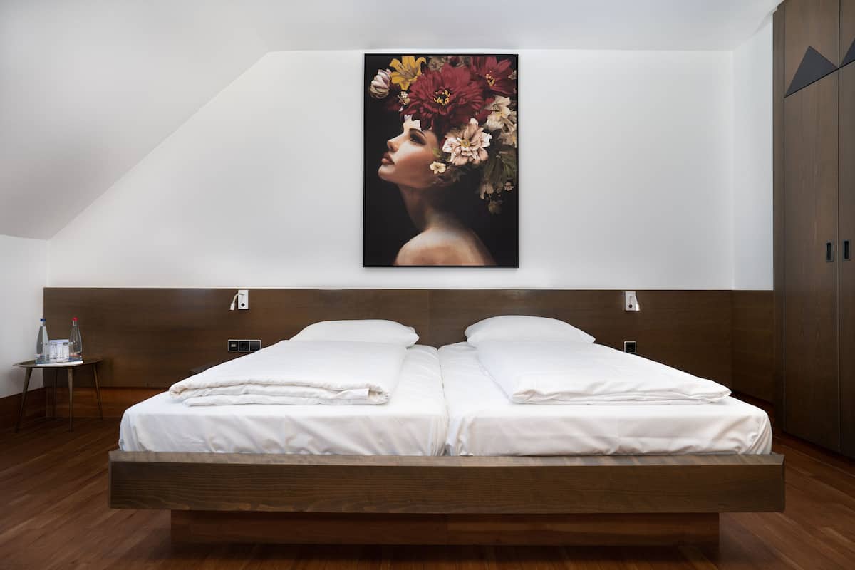 A modern bedroom with a large bed, a nightstand, and a wall-mounted painting.