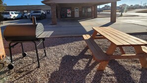 Un área de estar al aire libre con techo, una parrilla y una mesa de picnic.