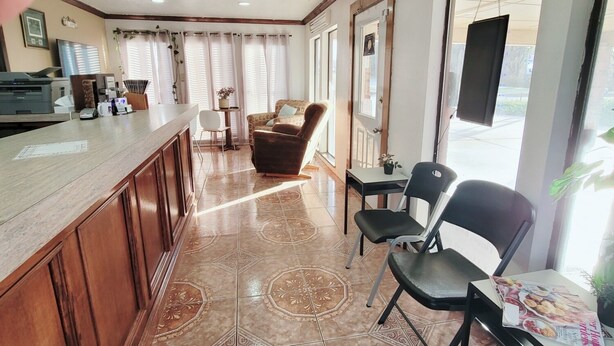 Una cocina amplia con una encimera larga, un comedor con sillas y un reloj en la pared.