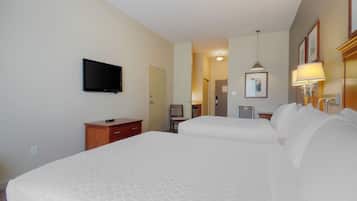 A hotel room with two beds, a TV, a desk, and a chair.