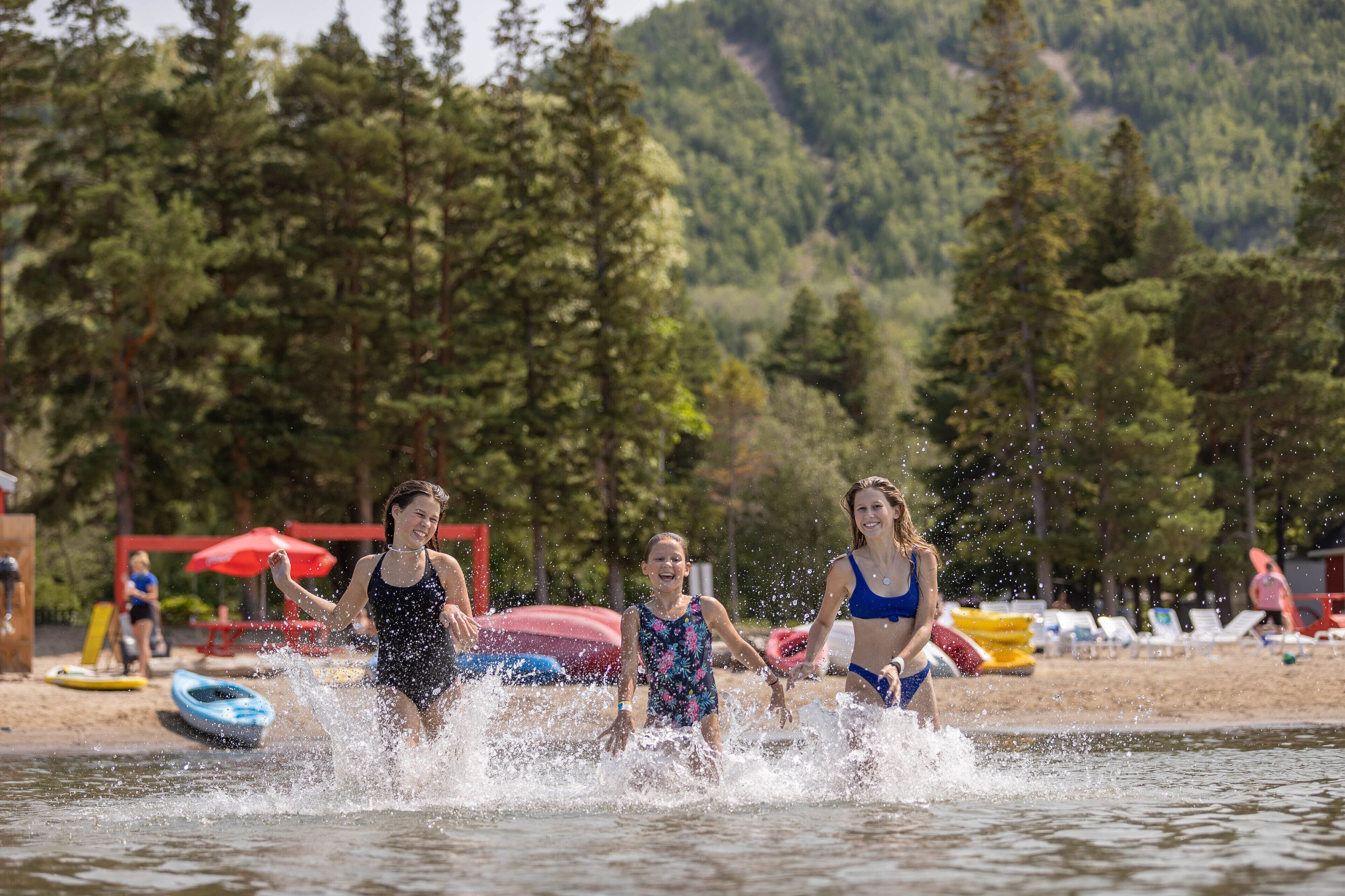 Un lago con gente en traje de baño y kayaks.
