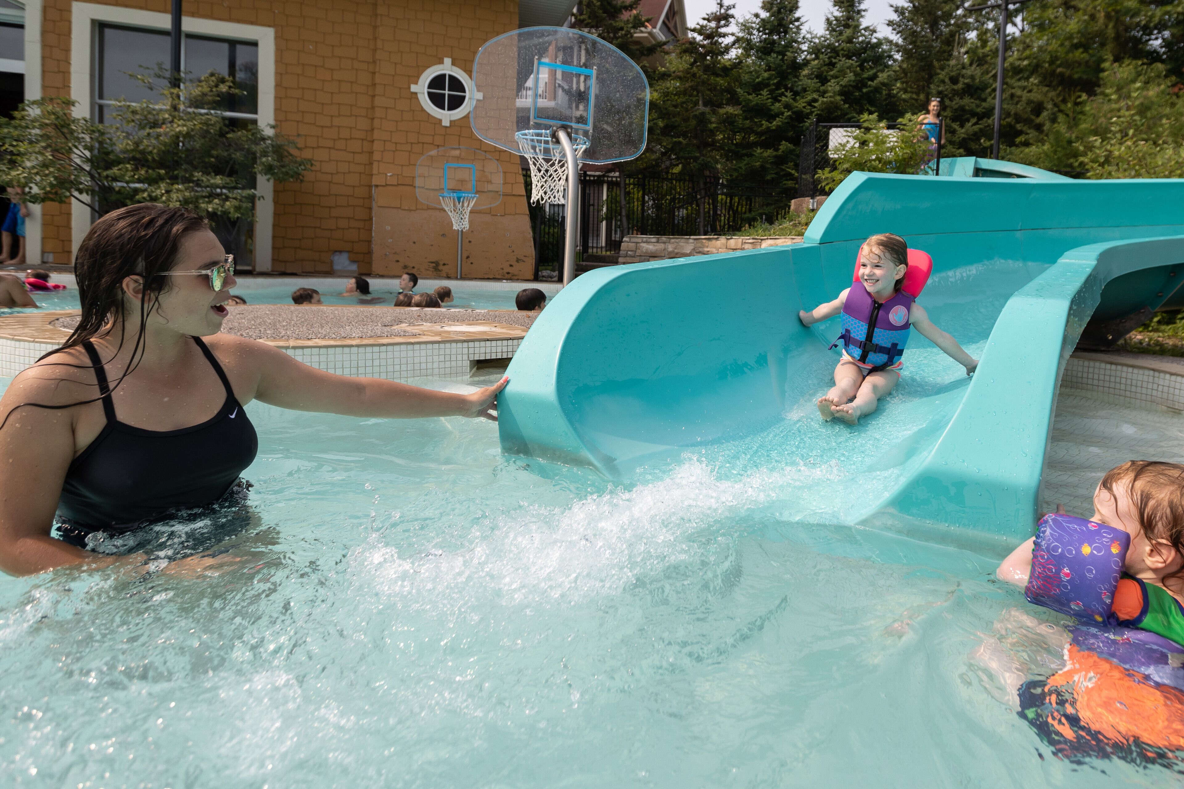 A water slide at a public facility with a basketball hoop in the background.