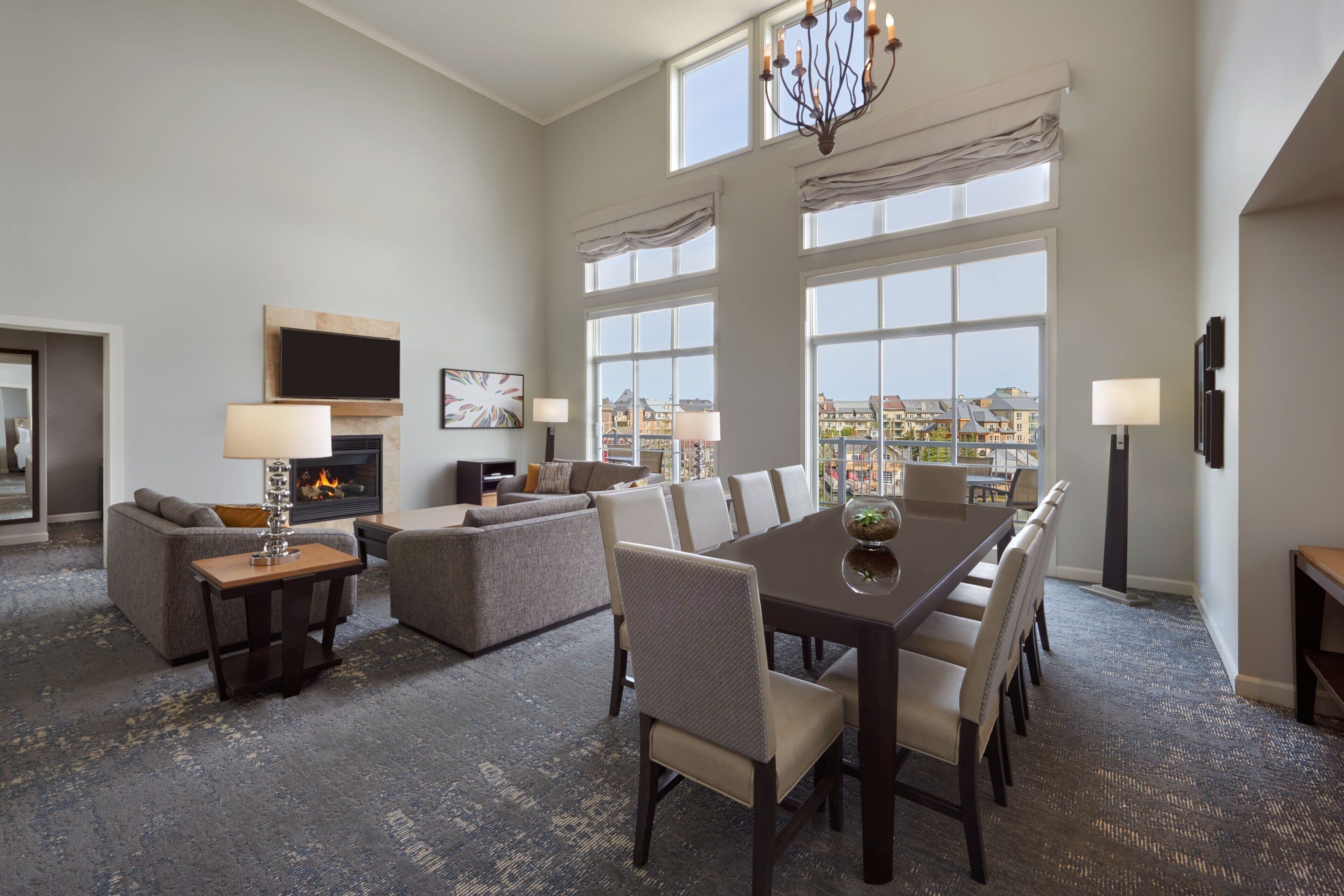 A spacious living room with a fireplace, large windows, and a dining area.