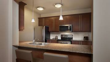 Una cocina moderna con encimeras de granito, electrodomésticos de acero inoxidable y armarios de madera.