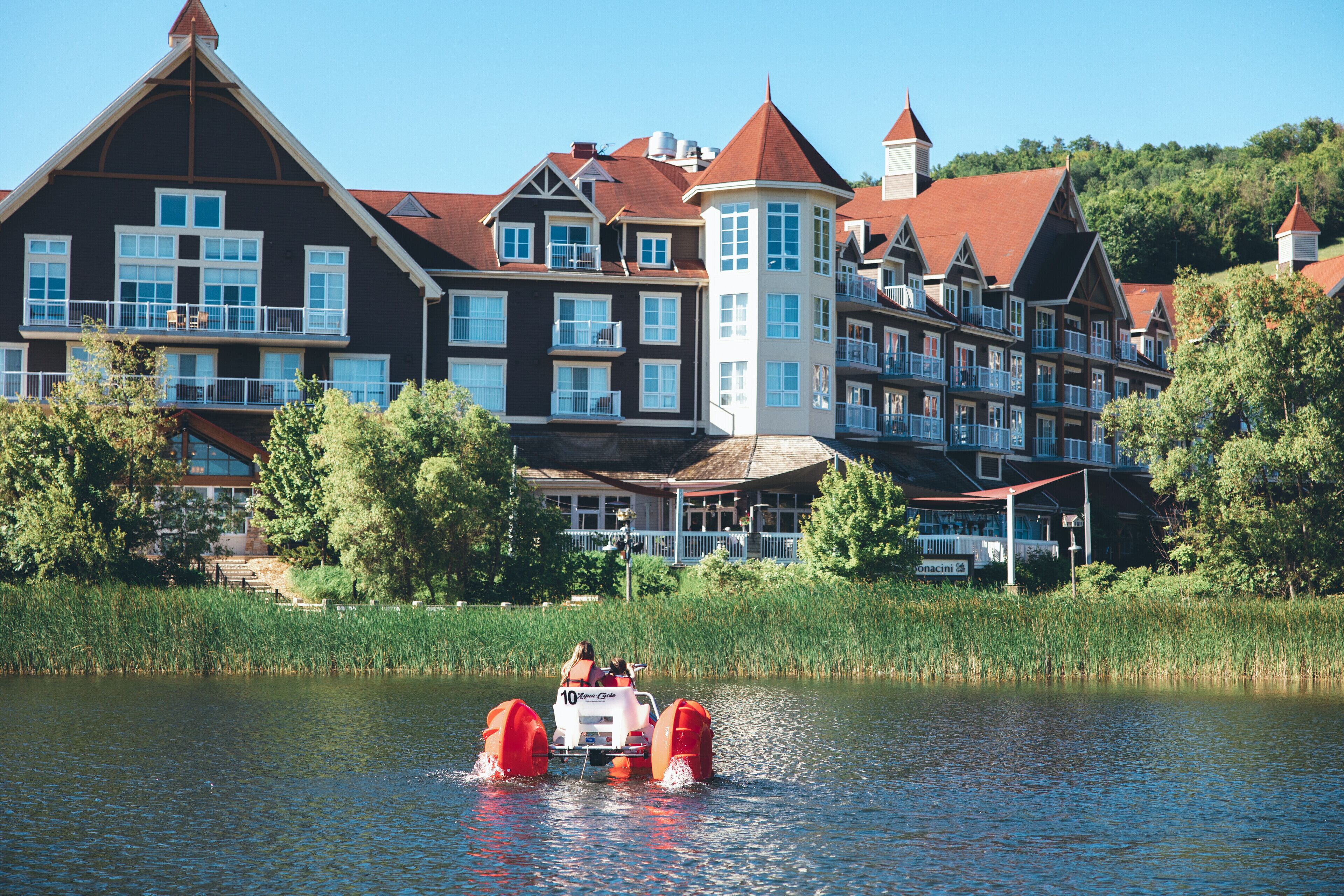A large, multi-story hotel with a prominent tower and a lake in the foreground.