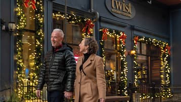 A couple standing in front of a building with a sign that reads "twist kitchen & cocktail."