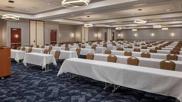 A conference room with rows of tables and chairs, a patterned carpet, and modern lighting fixtures.