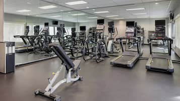A gym with various exercise equipment, including treadmills, ellipticals, and weight machines.
