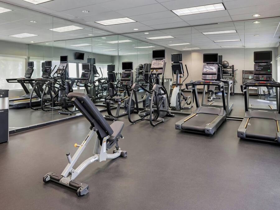 A gym with various exercise equipment, including treadmills, ellipticals, and weight machines.