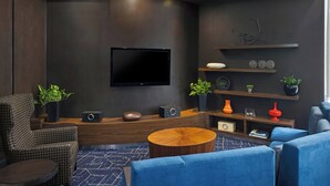 Una sala de estar moderna con televisor de pantalla plana, paredes oscuras, muebles de madera y elementos decorativos.