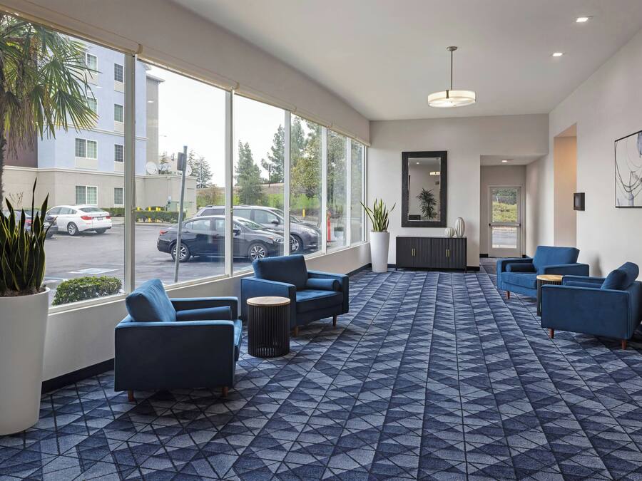 A modern lobby with large windows, blue seating, and a geometric patterned floor.