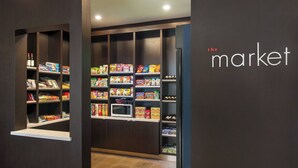 Interior de una tienda con estantes llenos de diversos productos, un microondas y un refrigerador.