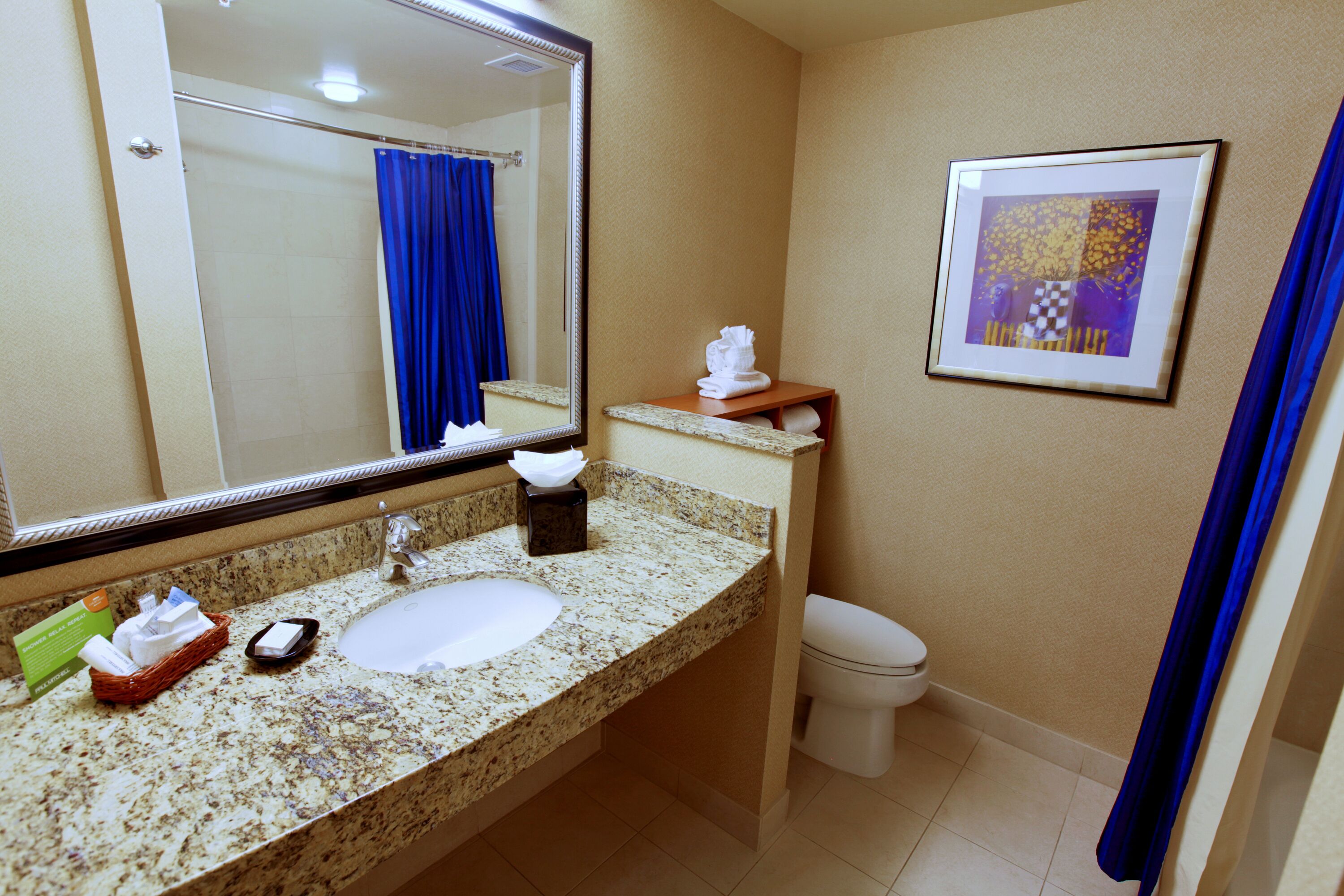 Un baño con lavamanos, espejo, toallero y retrete.