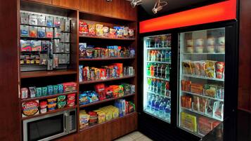 A vending machine area with microwaves and shelves stocked with snacks and beverages.