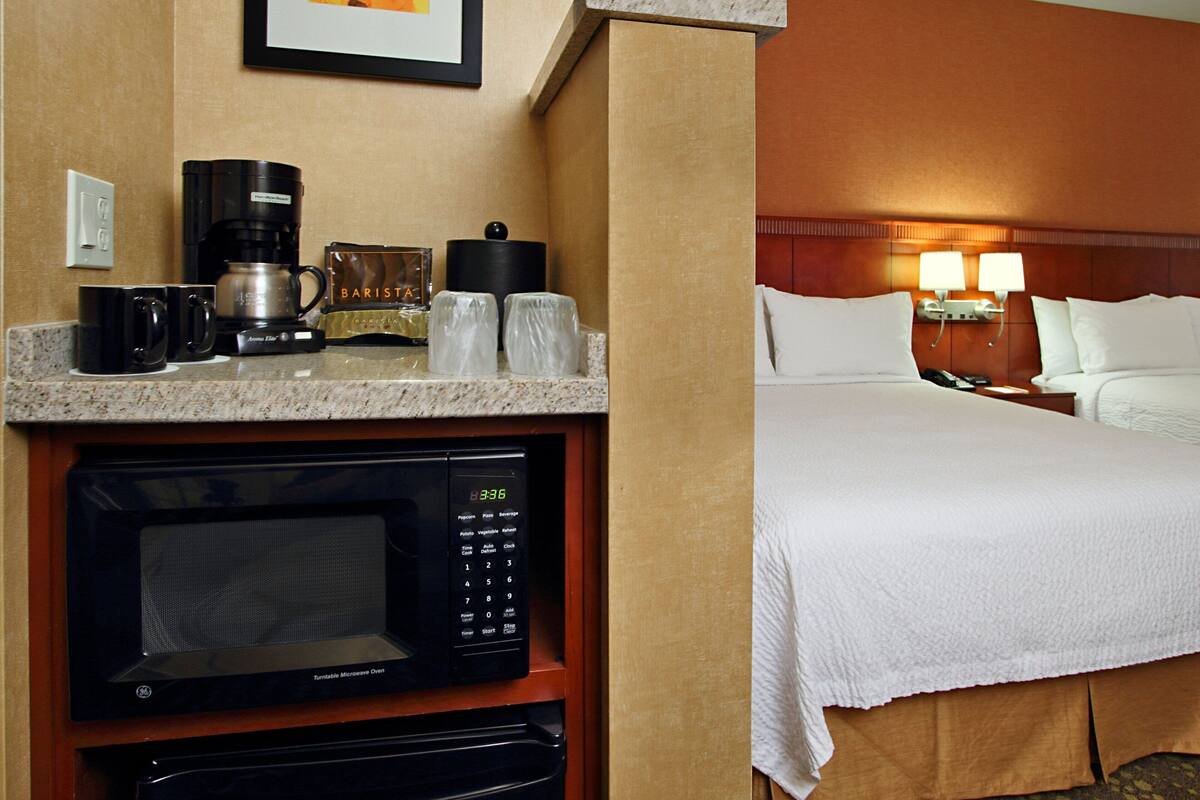 Une chambre d’hôtel dotée d’un coin cuisine comprenant un four à micro-ondes, une machine à café et une bouilloire.