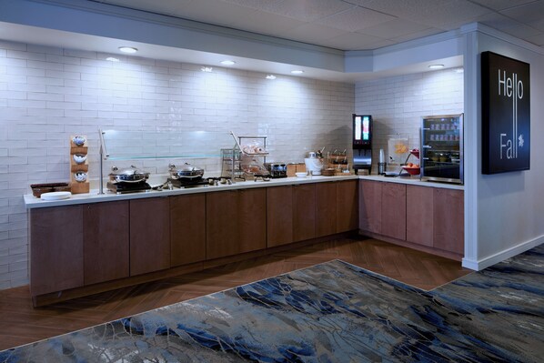 A modern kitchen with a breakfast bar, white tiled backsplash, and wooden cabinets.