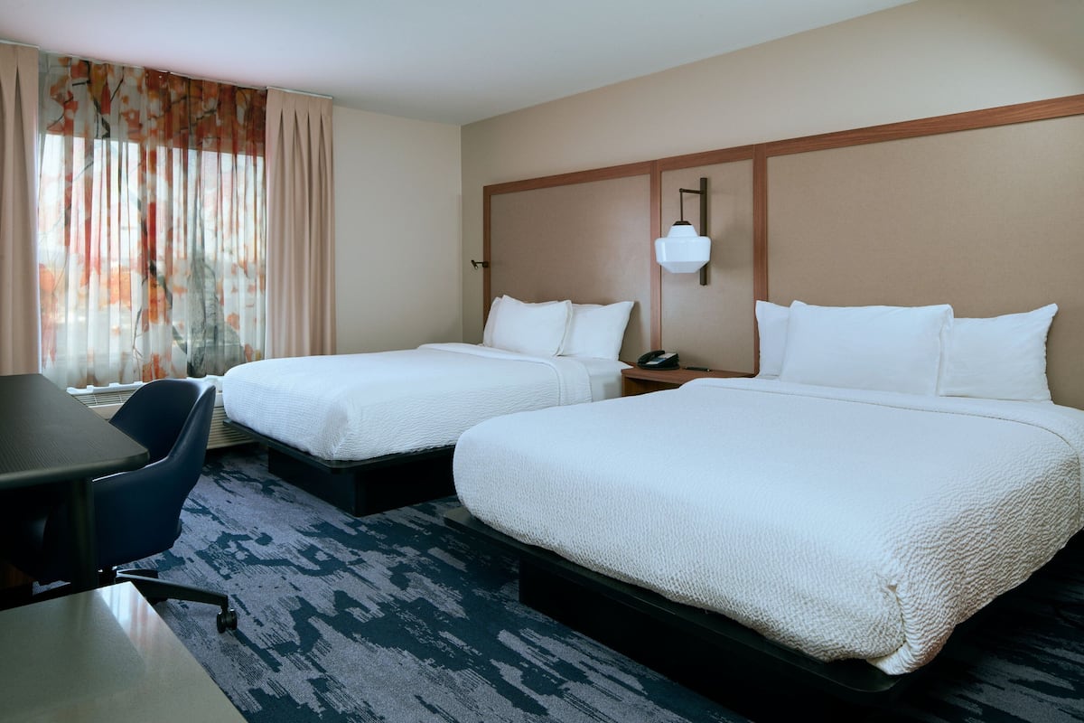 Habitación de hotel con dos camas, un escritorio y una silla.