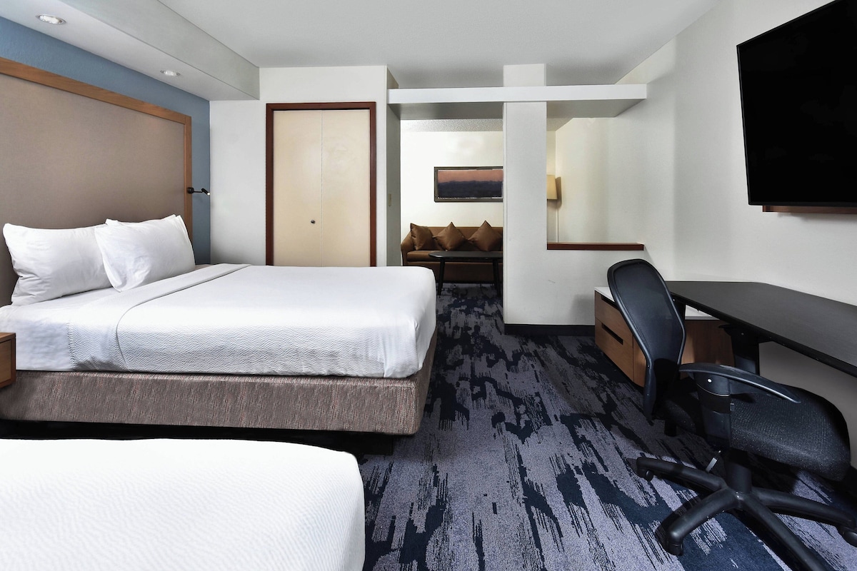 A hotel room with a bed, a desk, a chair, and a television.