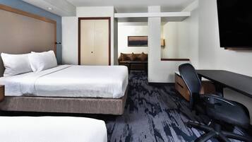 A hotel room with a bed, a desk, a chair, and a television.