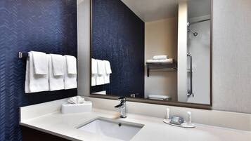 A modern bathroom with a large mirror, two sinks, and a shower.