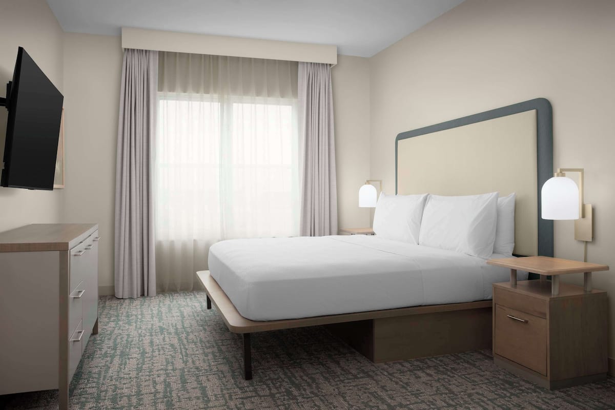 Une chambre d’hôtel équipée d’un lit, de tables de chevet, d’une télévision et d’un bureau.