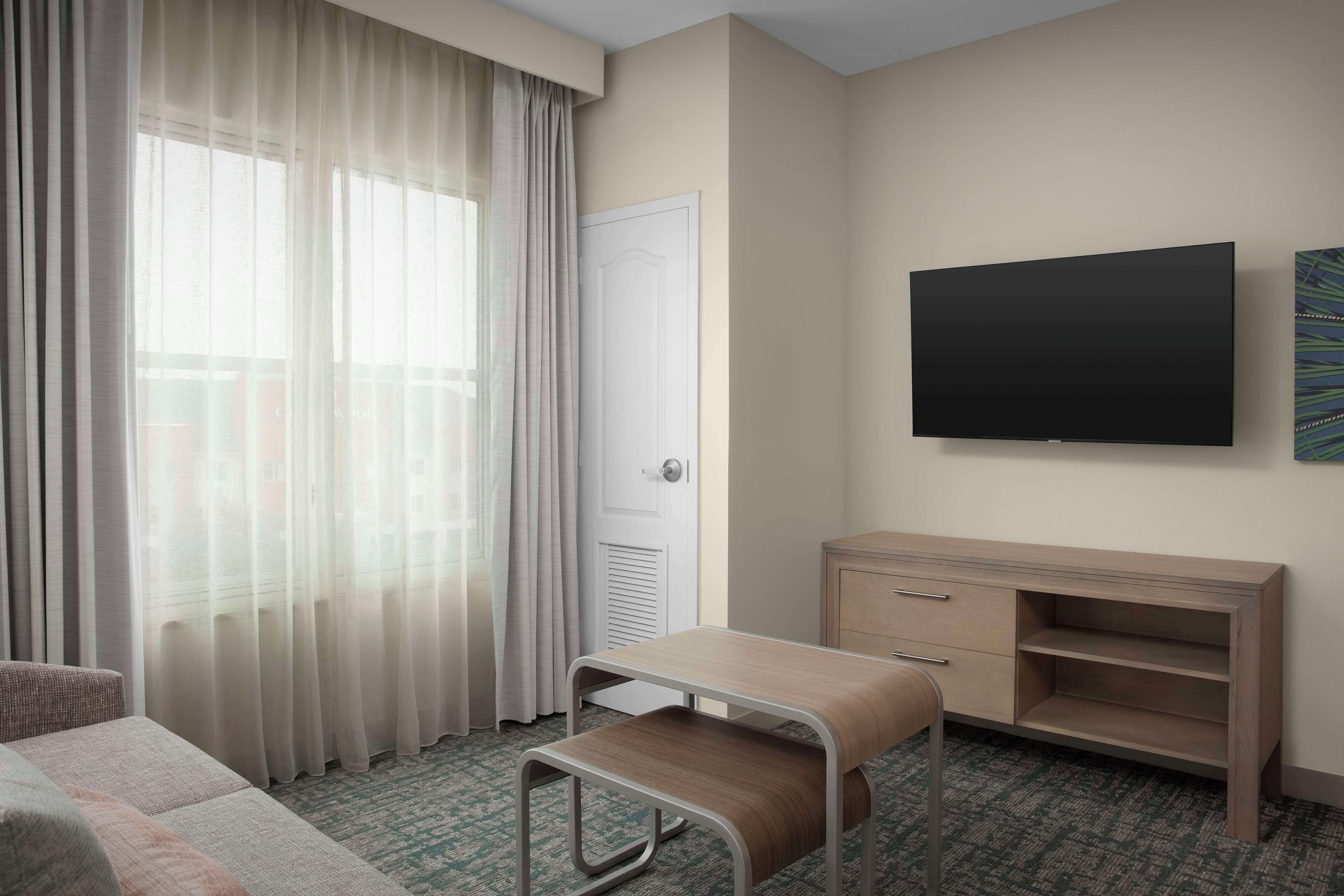 A hotel room with a bed, a desk, a chair, a TV, and a window with curtains.