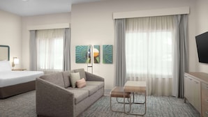 Une chambre d’hôtel avec un lit, un canapé, une petite table et un téléviseur.