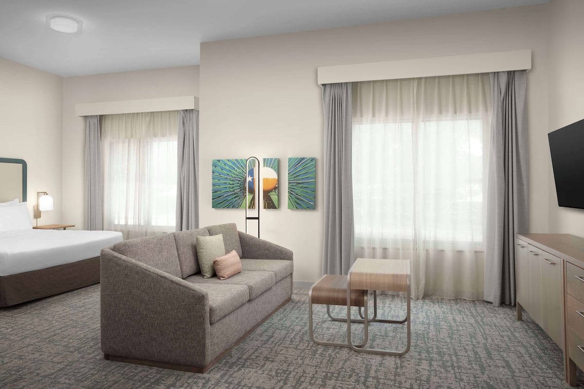 Une chambre d’hôtel avec un lit, un canapé, une petite table et un téléviseur.