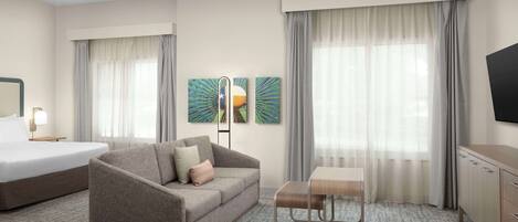 Une chambre d’hôtel avec un lit, un canapé, une petite table et un téléviseur.