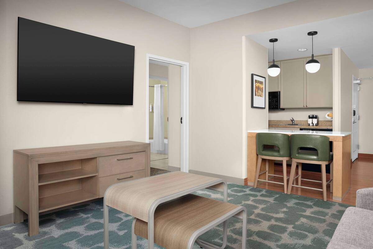 Une chambre à coucher moderne avec un lit, une table de chevet et un grand téléviseur fixé au mur.