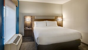 Una habitación de hotel con cama, mesitas de noche, un calefactor y lámparas fijadas a la pared.