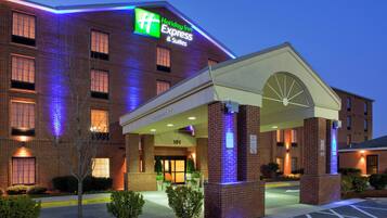 Edificio de Holiday Inn Express & Suites con fachada de ladrillo, entrada iluminada y señalización que indica 'CLEARANCE 11'6' estacionamiento.