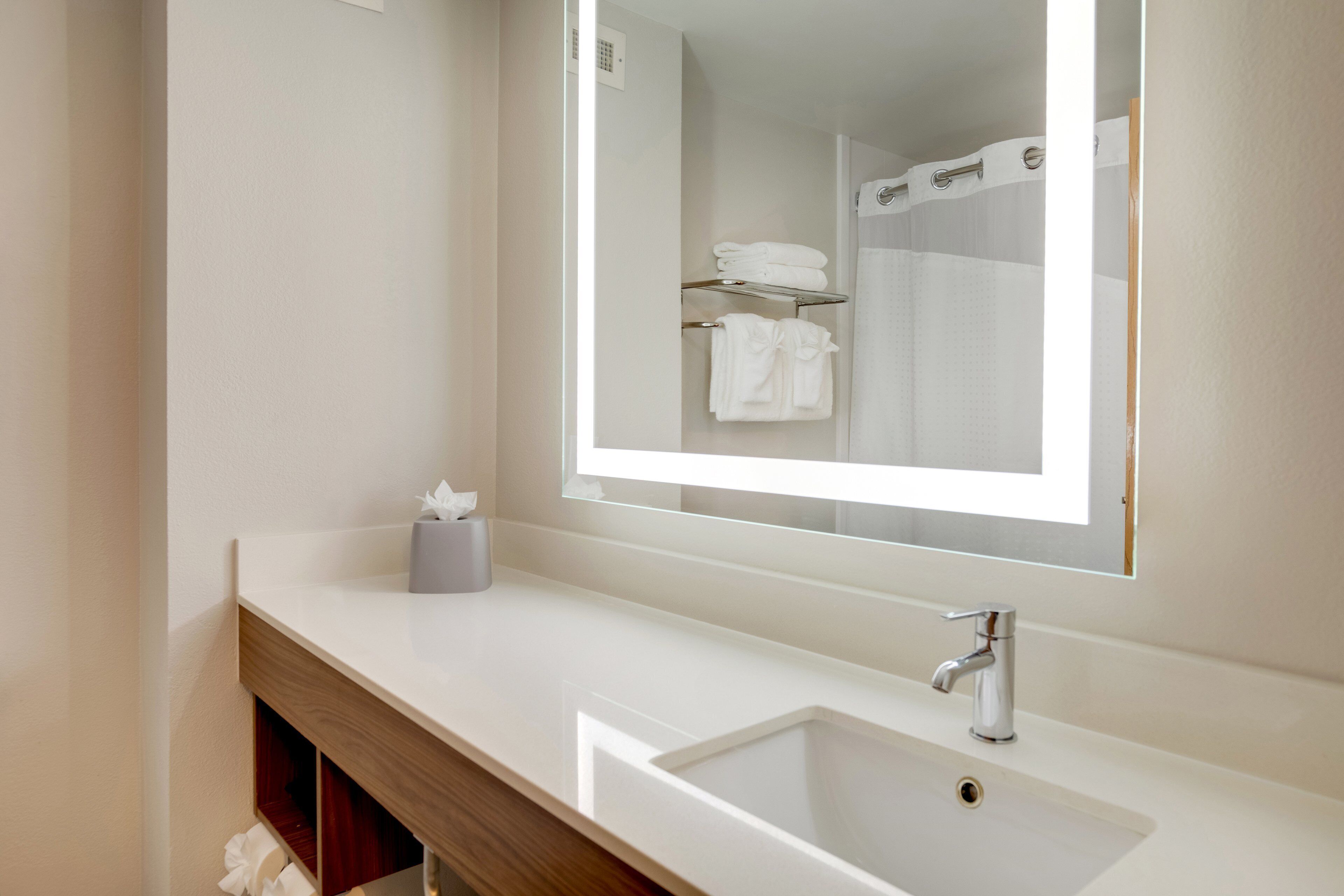 Une salle de bain moderne avec un lavabo blanc, un miroir et un porte-serviettes.