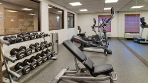 Un gimnasio con racks de pesas, mancuernas y equipo cardiovascular.