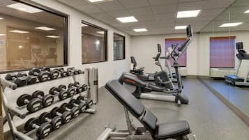 Un gimnasio con racks de pesas, mancuernas y equipo cardiovascular.