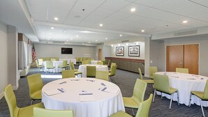 A conference room with multiple tables and chairs, a television, and framed artwork on the walls.
