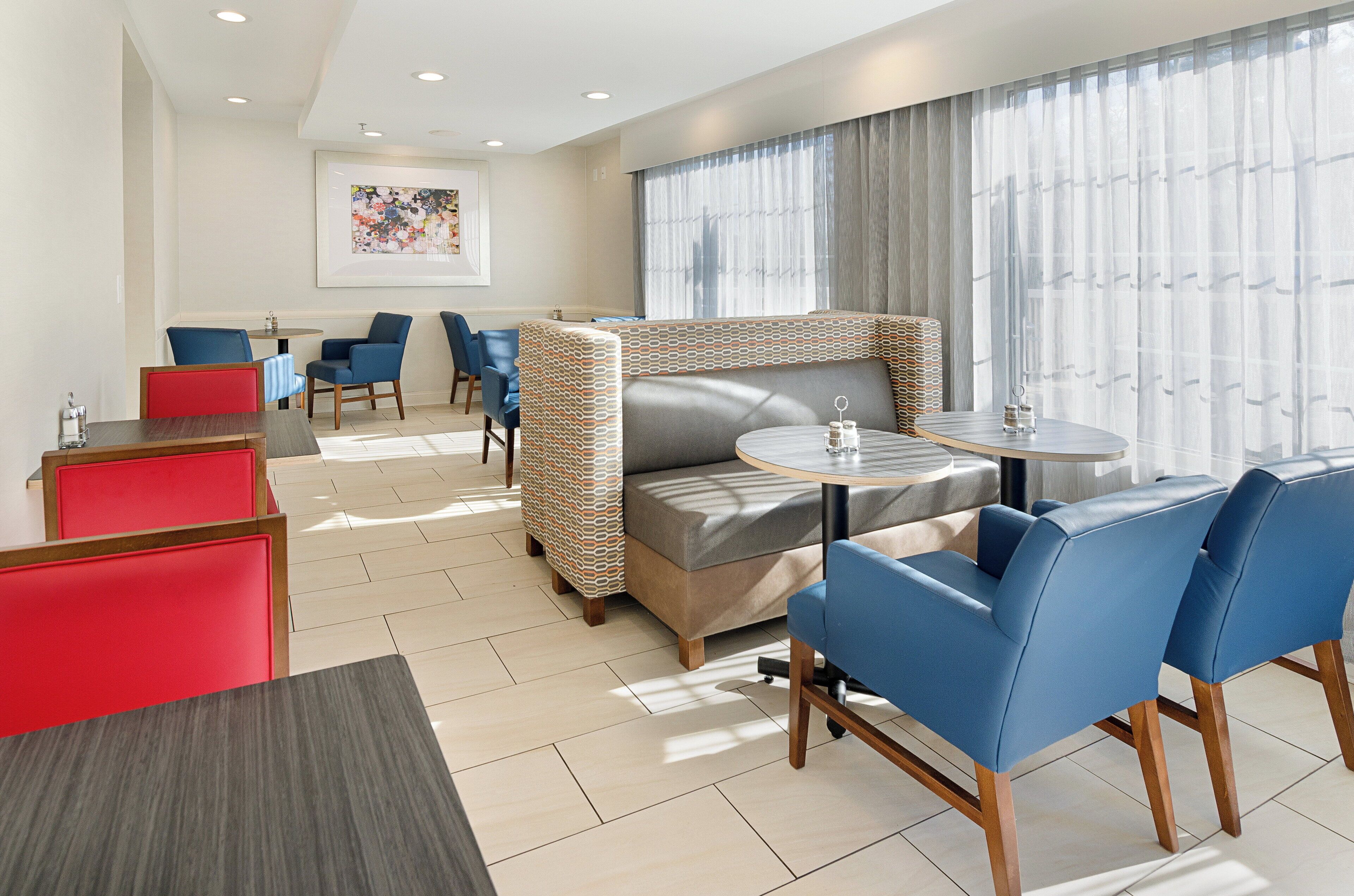 A hotel room with a sofa, two chairs, a small table, and a window with curtains.
