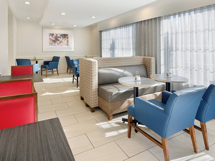 A hotel room with a sofa, two chairs, a small table, and a window with curtains.